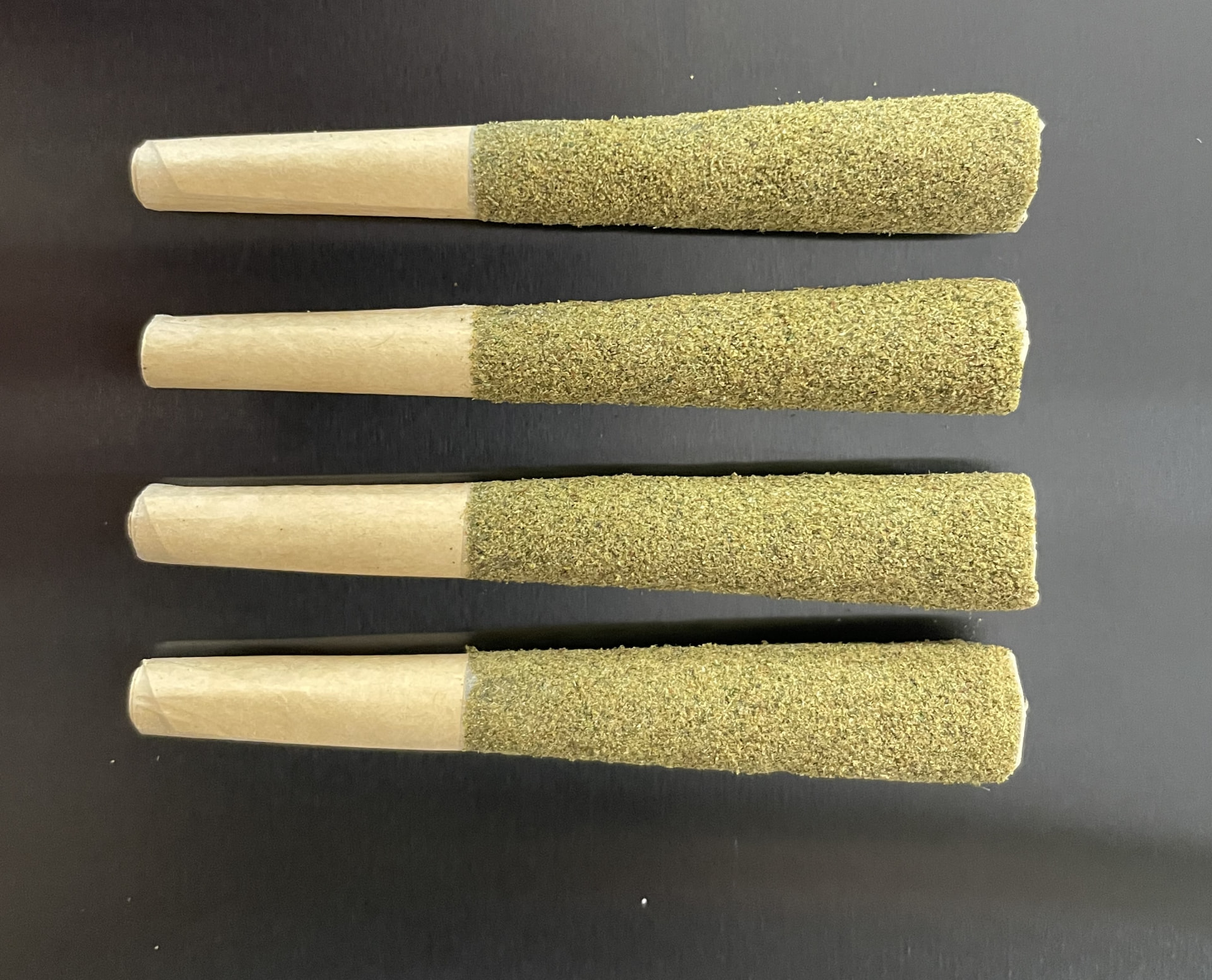 Four kief-coated pre-rolls showing an even, uniform finish